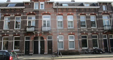 een bakstenen gebouw met ramen en een auto die aan de kant van de weg geparkeerd staat