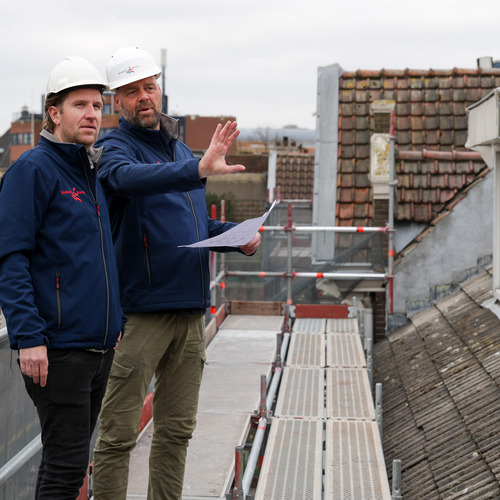 Twee mannen met helmen die zich op een dak bevinden