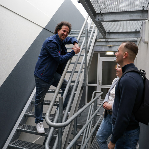 Man op de trap praat tegen een man en vrouw