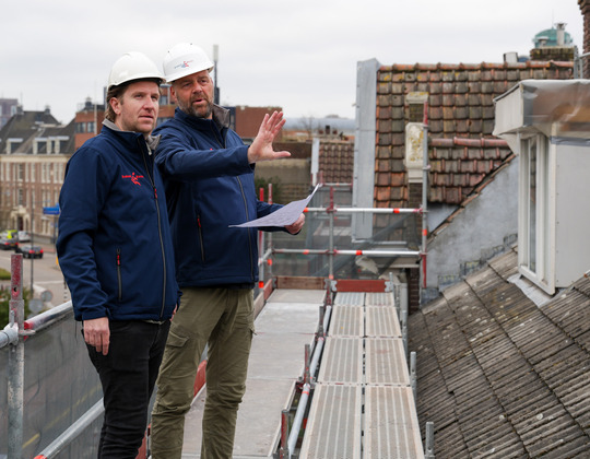 Twee mannen met helmen die zich op een dak bevinden