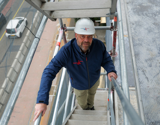 Op de afbeelding staat een man die een veiligheidshelm draagt