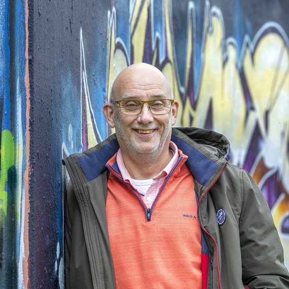 Een man die zich voor een muur met graffiti bevindt
