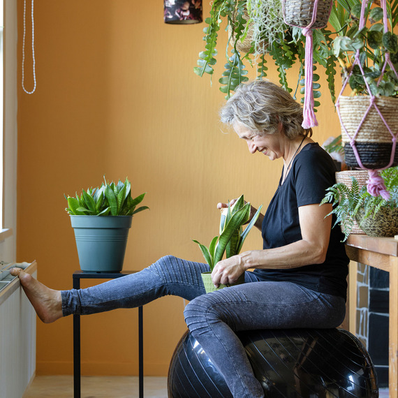 Dame op een stoel verzorgt planten