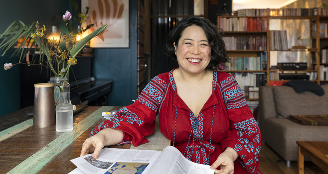 Een vrouw zittend aan een tafel met een boek