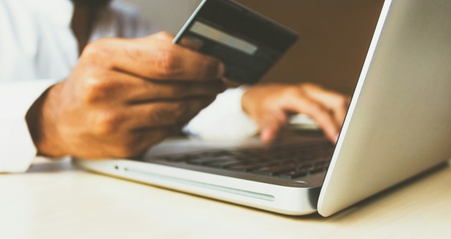 Een sociale huurwoning zoeken via het web. Betaal niet voor niks! een persoon die een creditcard vasthoudt en op een laptop typt