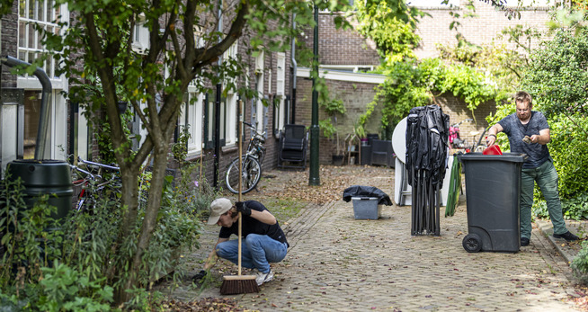 Voorjaarsschoonmaak? Vergeet de brandgang niet! een persoon die bladeren op een trottoir veegt
