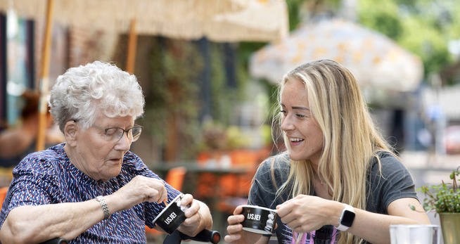 een vrouw en een oudere vrouw die aan een tafel zitten