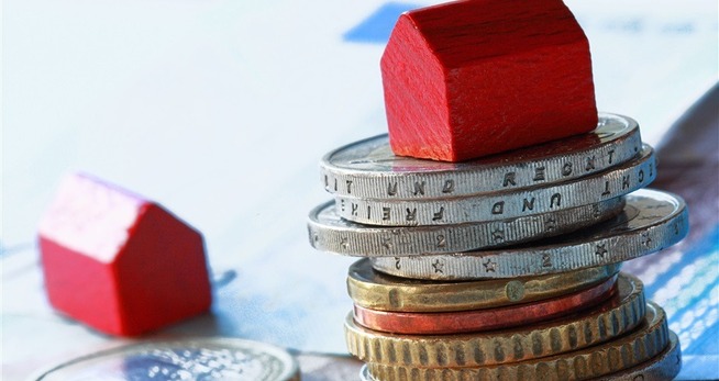 huurverhoging Een stapel munten en een rood huis