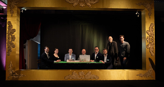 een groep mensen die aan een tafel zitten