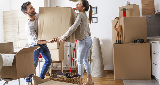 Man en vrouw dragen een kartonnen verhuisdoos