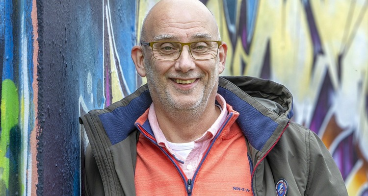 Een man die zich voor een muur met graffiti bevindt