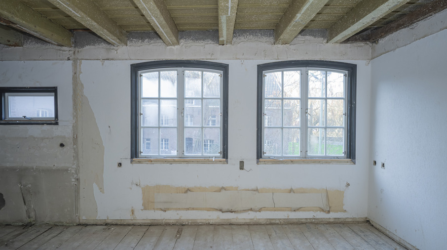 een kamer met een witte muur en ramen