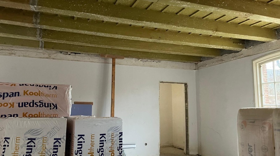 een kamer met witte muren en houten balken