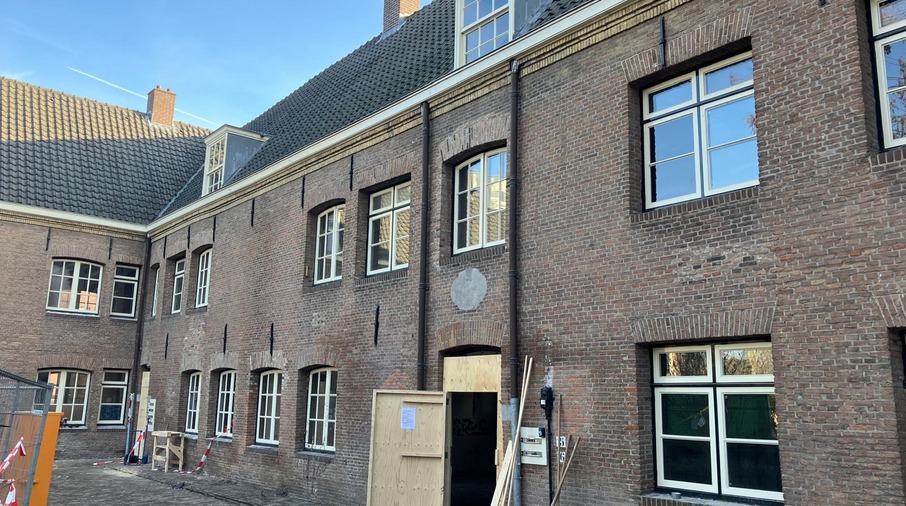 een bakstenen gebouw met een open deur en op de achtergrond Birmingham Back to Backs