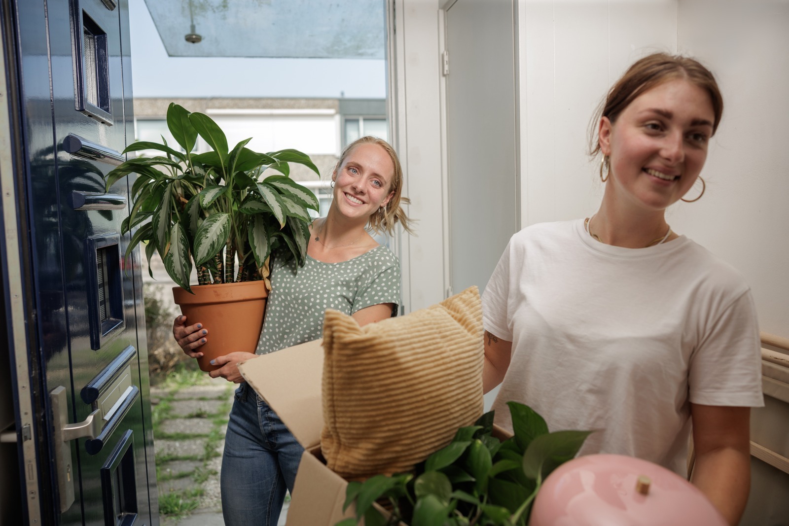 Twee jonge dames met verhuisdozen en een plant