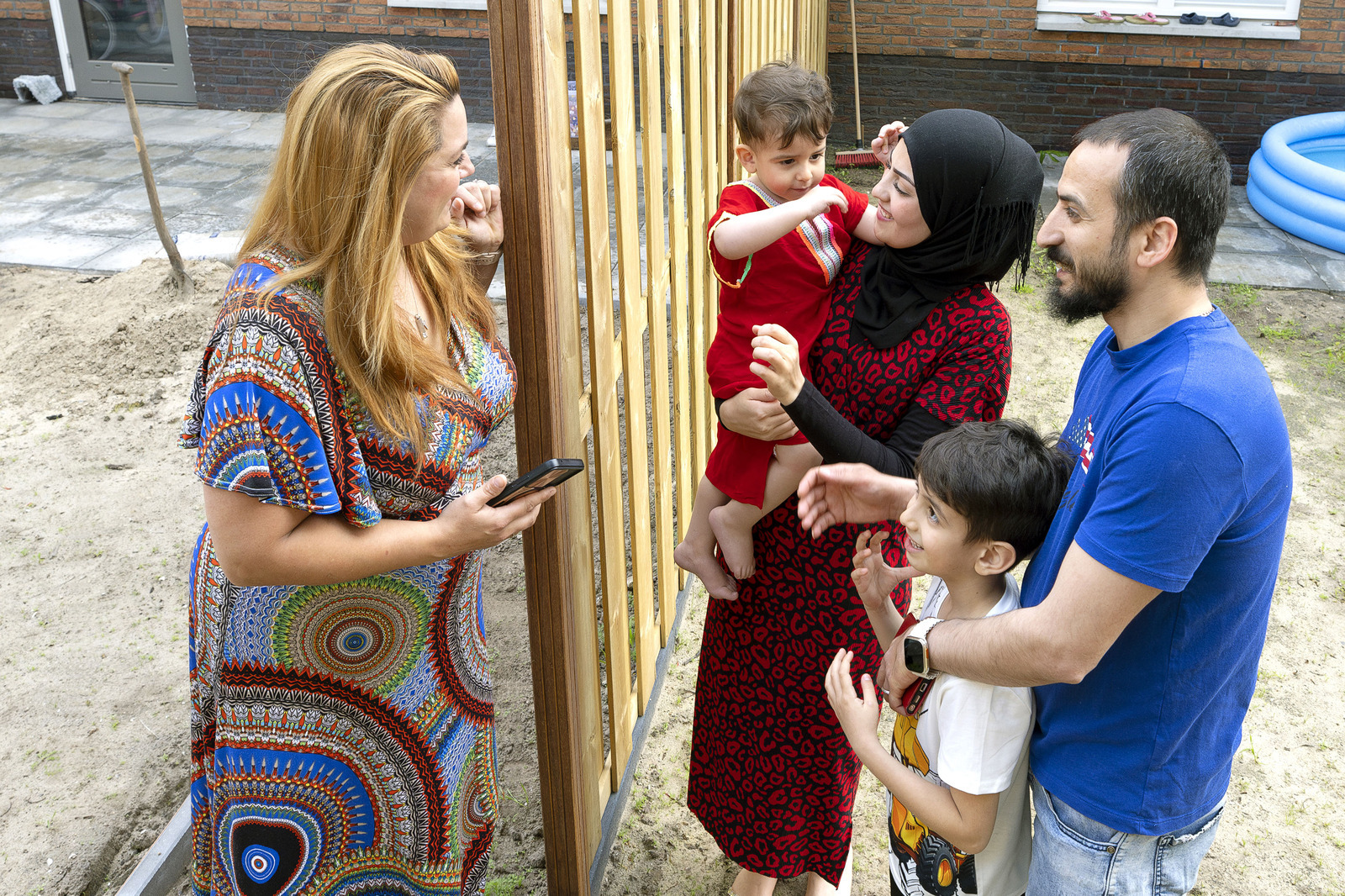 Mensen maken een praatje bij een tuinschutting