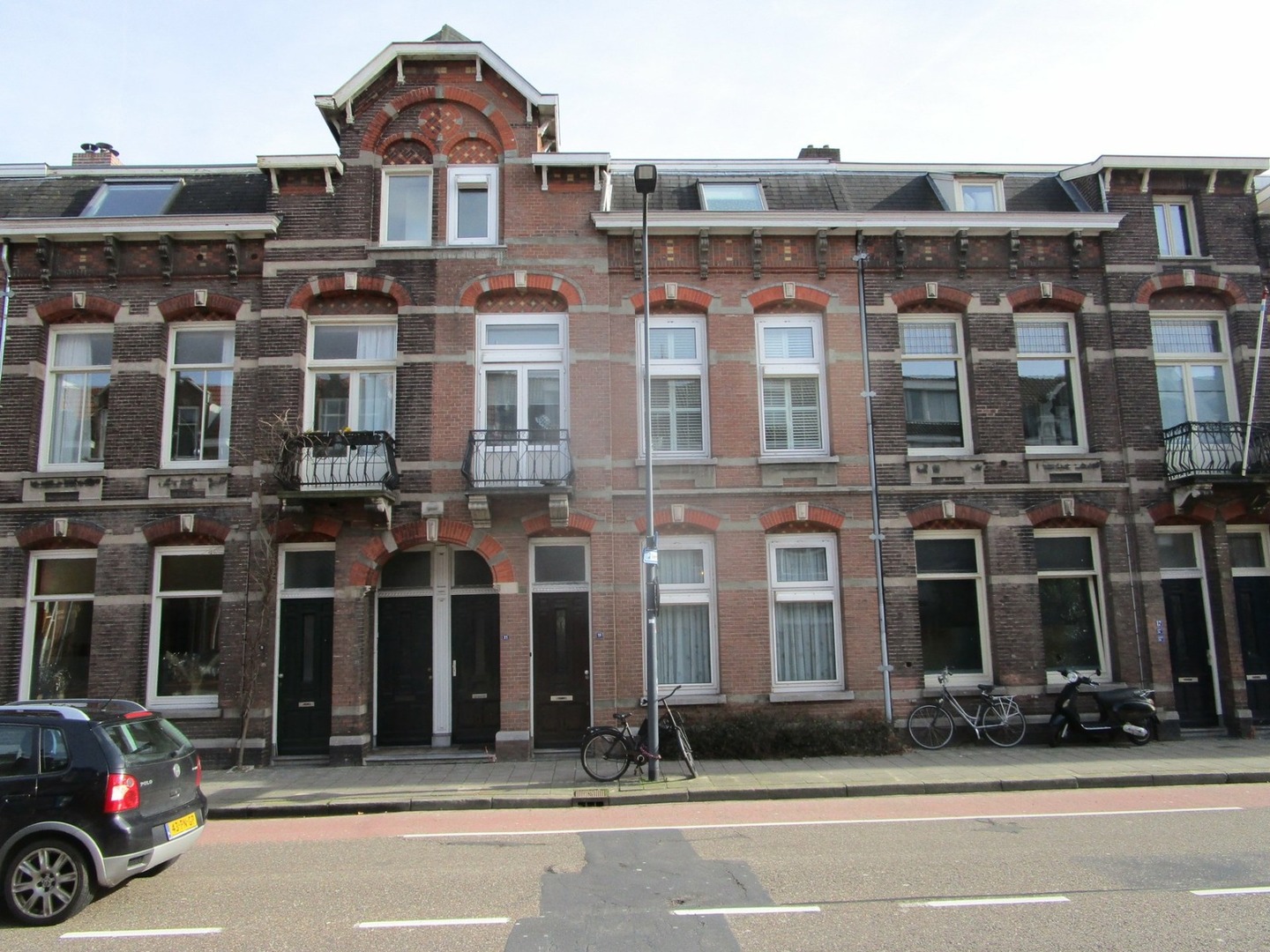 een bakstenen gebouw met ramen en een auto die aan de kant van de weg geparkeerd staat