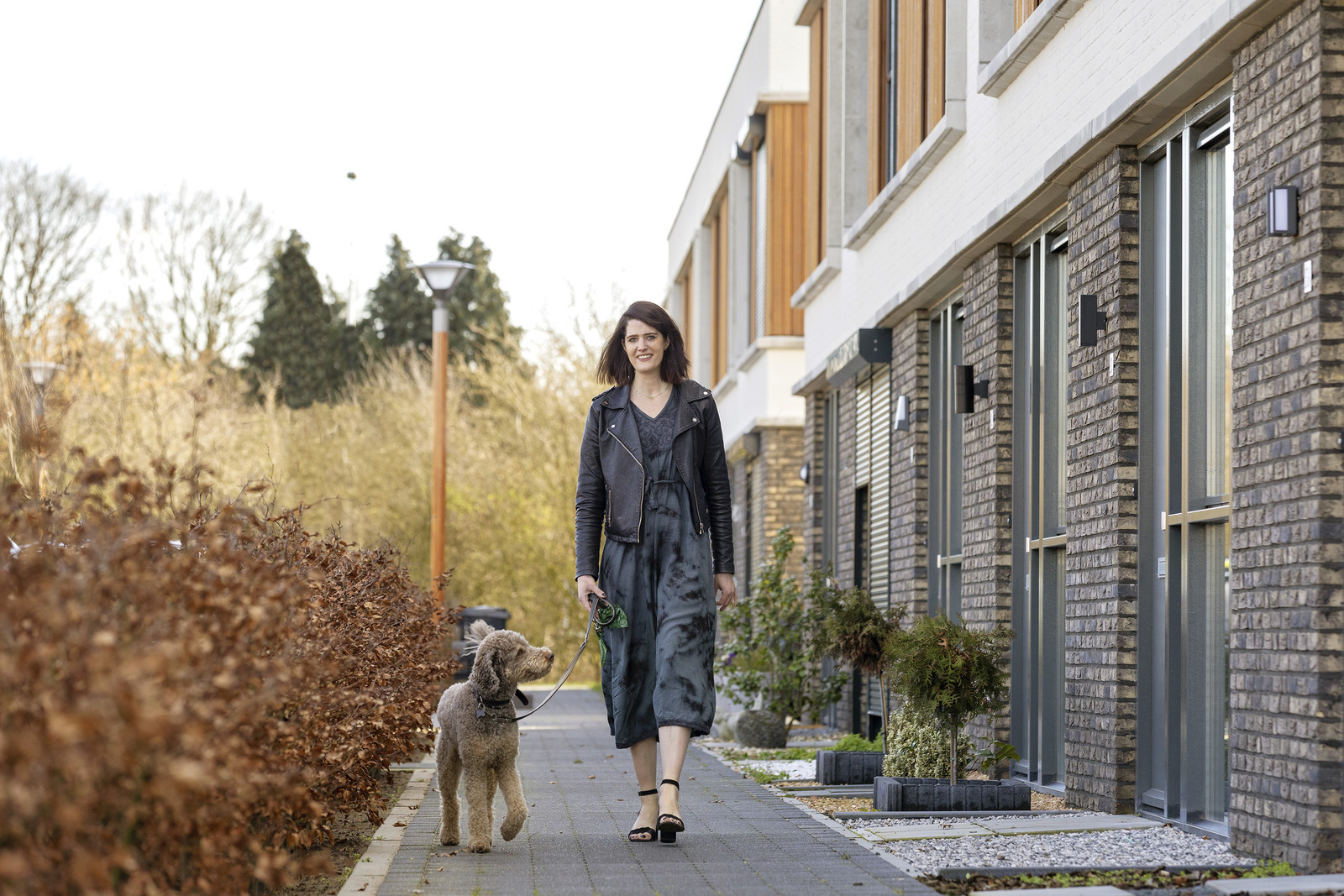 Een vrouw die een hond op een trottoir uitlaat