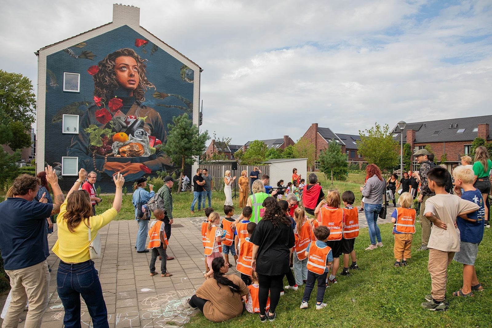 Op de afbeeling staan mensen die naar een muurschildering op een huis kijken