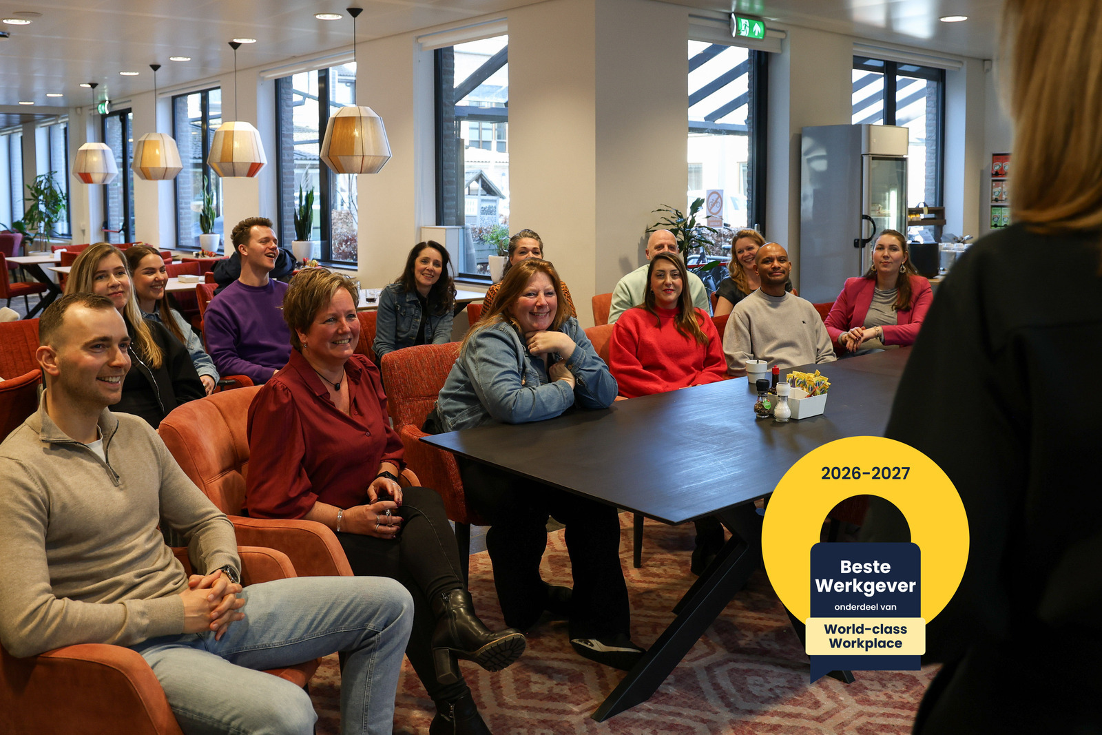 Groep mensen die zitten, rechts een logo