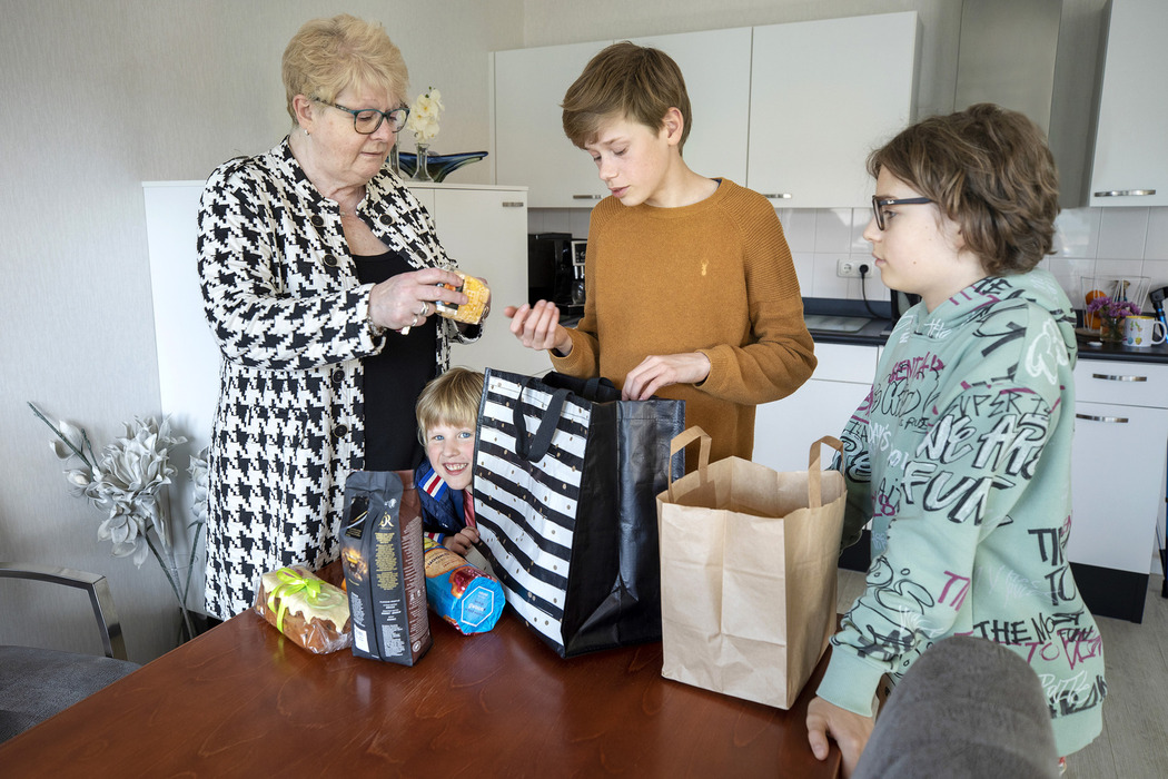 een groep mensen die zich rond een tafel met zakken bevinden